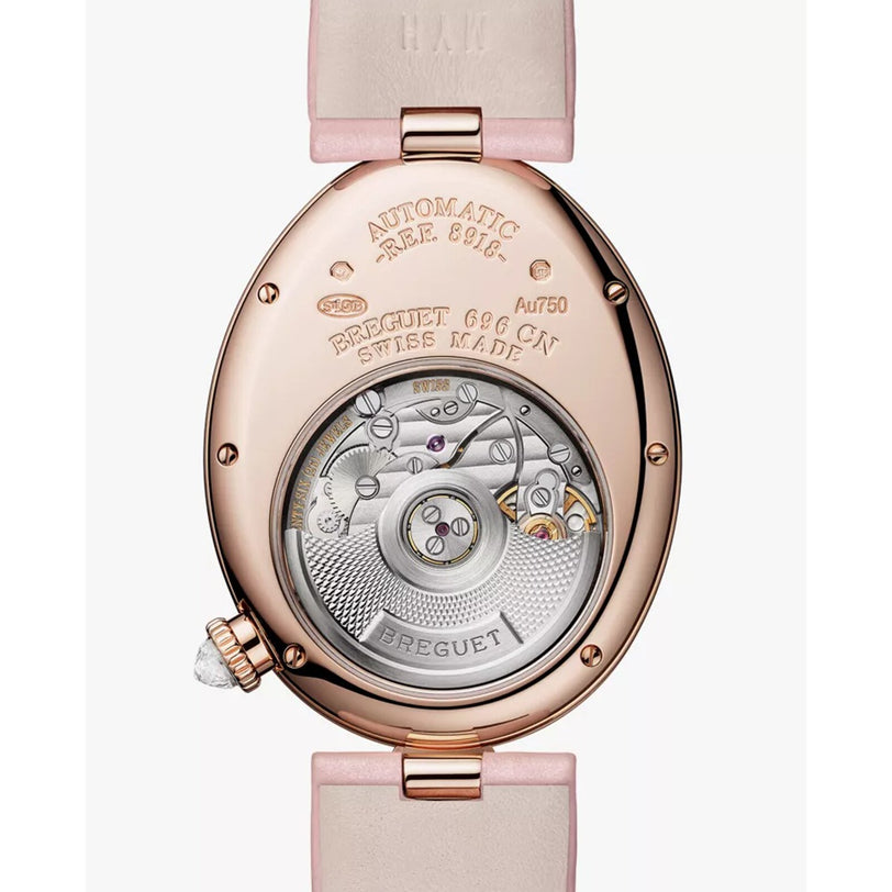 The Breguet Reine de Naples 8918 showcases its intricate automatic movement through a transparent case back, features detailed engravings, and comes with a pink leather strap—a true symbol of feminine elegance.