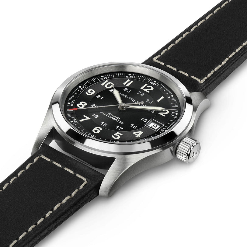 A close-up of the Hamilton Khaki Field Auto, a rugged military-inspired watch featuring a black dial with white numerals, date display, and a black leather strap accented by white stitching.