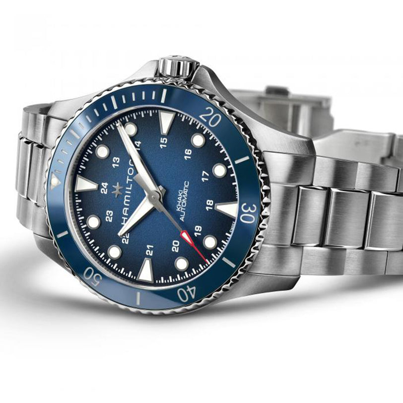 The Hamilton Khaki Navy Scuba Auto is a stainless steel wristwatch with a blue dial and bezel, luminous markers, date display, and metal link bracelet—a high-performance aquatic-inspired timepiece.