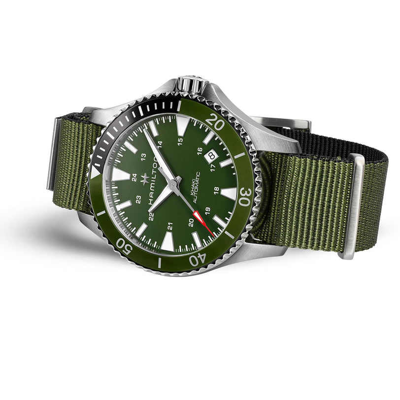 The Hamilton Khaki Navy Scuba Auto features a silver case, green face with white hour markers, and a green nylon strap. Showcasing Swiss-made movement, this watch exudes nautical style on a crisp white background.
