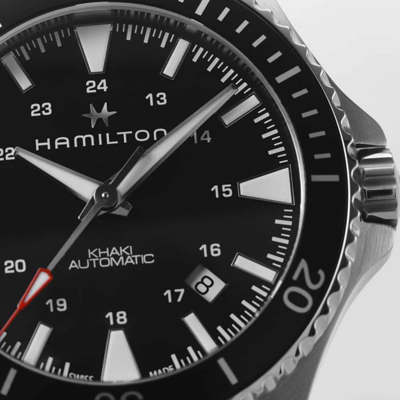 Close-up of the Hamilton Khaki Navy Scuba Auto watch, showcasing its black dial, white hour markers, date window, and stainless steel bezel—designed for precision and performance.