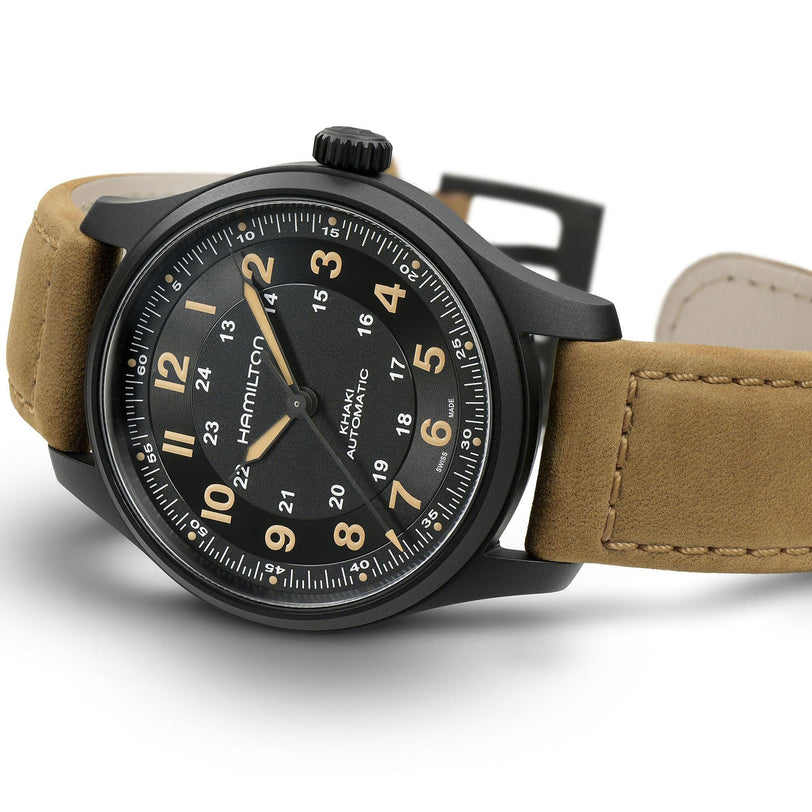 The Hamilton Khaki Field Titanium Auto watch features a stylish black dial and tan leather strap, displayed at an angle to highlight its classic military-inspired field watch design.
