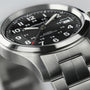 Close-up of the Hamilton Khaki Field Auto, a military-inspired watch with automatic movement, stainless steel band, black dial with Arabic numerals, date window, and 24-hour markings.