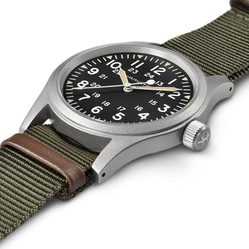 The Hamilton Khaki Field Mechanical 38mm showcases a black dial with white numerals, an olive green NATO strap with brown leather accent, and is encased in durable stainless steel.