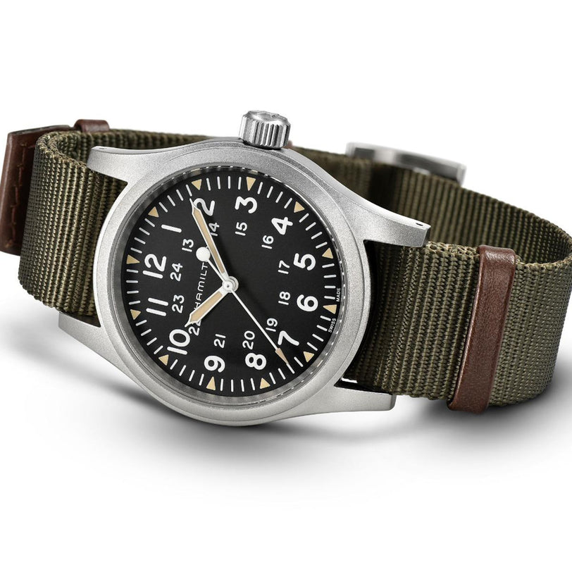 The Hamilton Khaki Field Mechanical 38mm features a black dial with white numerals, a green NATO strap with brown leather accents, and a stainless steel case, shown on a white background.