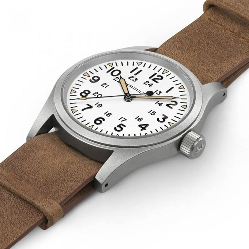 The Hamilton Khaki Field Mechanical is a classic military watch featuring a white dial with black numerals, a brown leather strap, and a silver case, shown here displaying the time at 10:10.