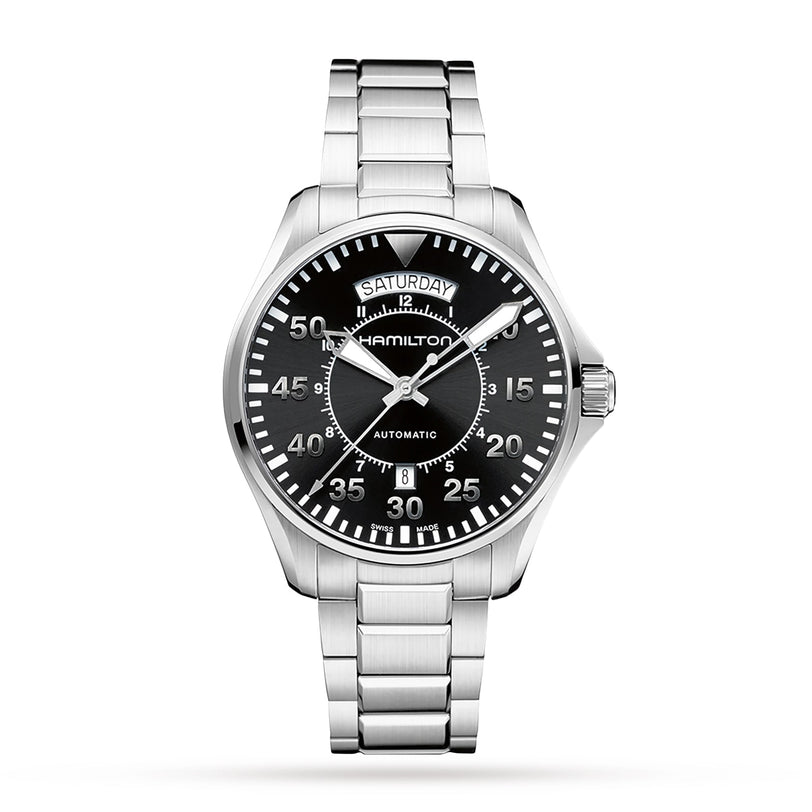The Hamilton Khaki Aviation Pilot Day Date Auto features a stainless steel case, black dial with white numerals, automatic movement, day and date display, and metal link bracelet, shown against a white background.