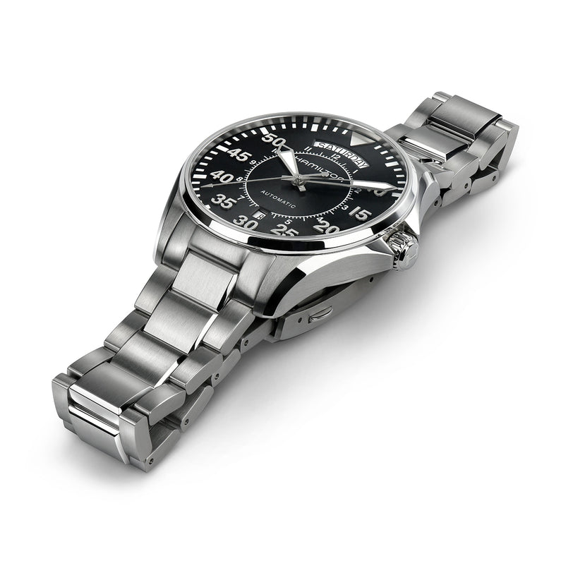 The Hamilton Khaki Aviation Pilot Day Date Auto is a vintage-style stainless steel aviator watch with a black dial, white numerals, and metal link band, shown at an angle on a white background.