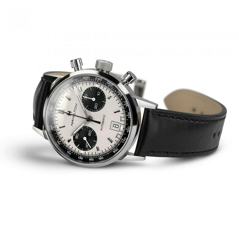 The Hamilton American Classic Intra-Matic Auto Chrono watch features a black leather strap, silver dial, and two black subdials, displayed at an angle.