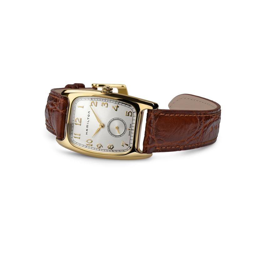 The Hamilton American Classic Boulton Quartz features a gold-tone case, square white dial, Swiss precision, brown leather strap, Arabic numerals at 12, 3, and 9 o’clock, and a small subdial at 6.