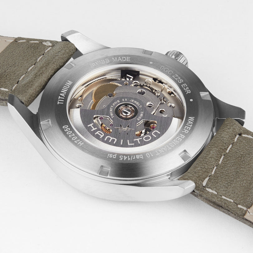 Close-up of the Hamilton Khaki Field Titanium Auto watch, showing its transparent case back that reveals the mechanical movement and engraved details on the metal rim.