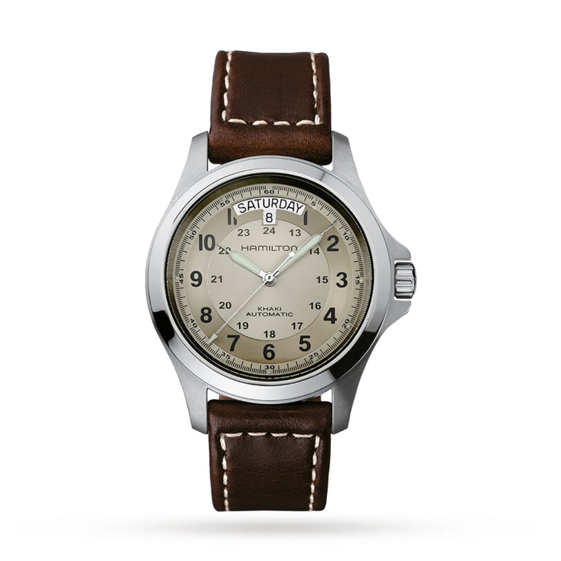 The Hamilton Khaki Field King Auto features a beige dial with black numerals, military time display, day-date at 12 oclock, and a brown leather strap with white stitching.