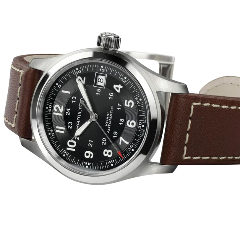 The Hamilton Khaki Field Auto features a black dial with white numerals, date display at 3 o’clock, and a brown leather strap with white stitching, all in a durable, military-inspired design.