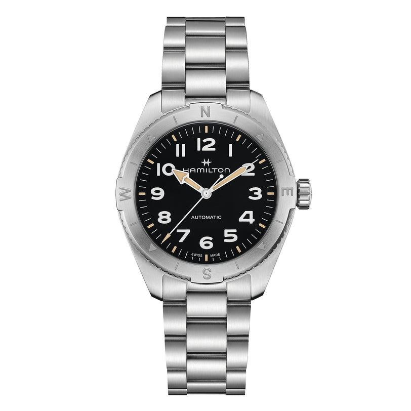 The Hamilton Khaki Field Expedition Auto is a stainless steel automatic watch featuring a black dial, silver Super-LumiNova hands, Arabic numerals, and a metal link bracelet.