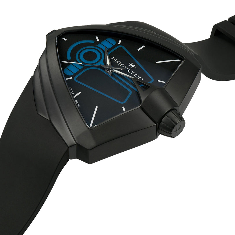 The Hamilton Ventura XXL Bright Dune Limited Edition wristwatch, featuring a futuristic black triangular case, blue accents, a rubber strap, and exclusive commemorative packaging, is displayed at an angle on a white background.