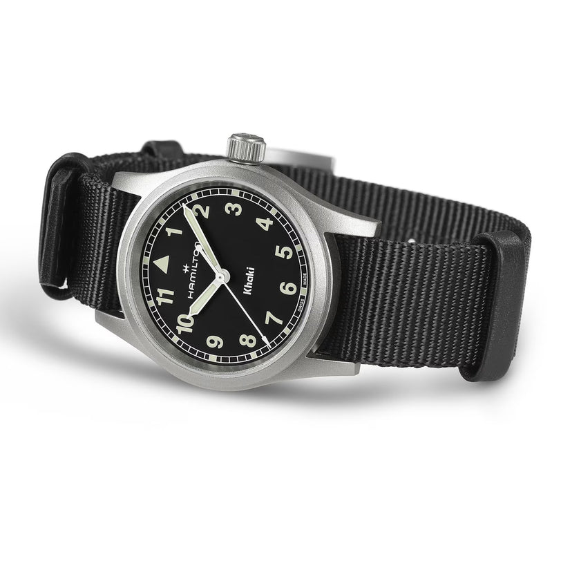 The Hamilton Khaki Field Quartz 33mm, a military-inspired watch, features a black dial with white numerals, luminous hands, and a black NATO strap. Shown angled on a white background.