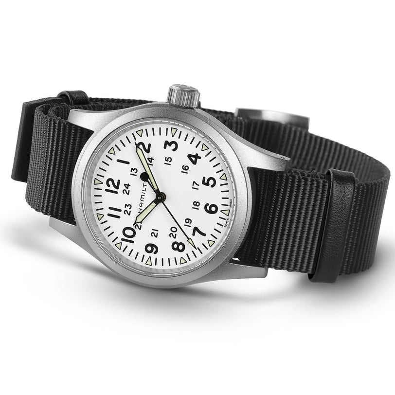 The Hamilton Khaki Field Mechanical wristwatch features a silver case, white dial with black Arabic numerals, date display, and a black NATO strap, shown on a white background.