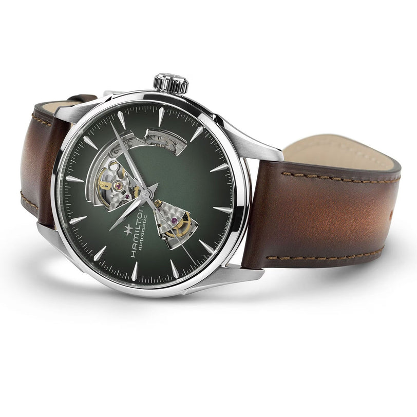The Hamilton Jazzmaster Open Heart Auto 42mm features a green open-heart dial that reveals part of its inner mechanism, set in a silver case with a brown leather strap.