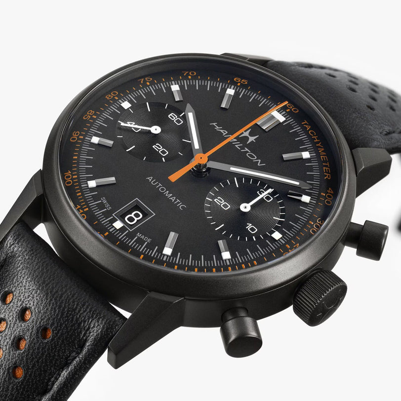 Close-up of the Hamilton American Classic Intra-Matic Auto Chrono, a black chronograph watch featuring a perforated leather strap and orange accents.