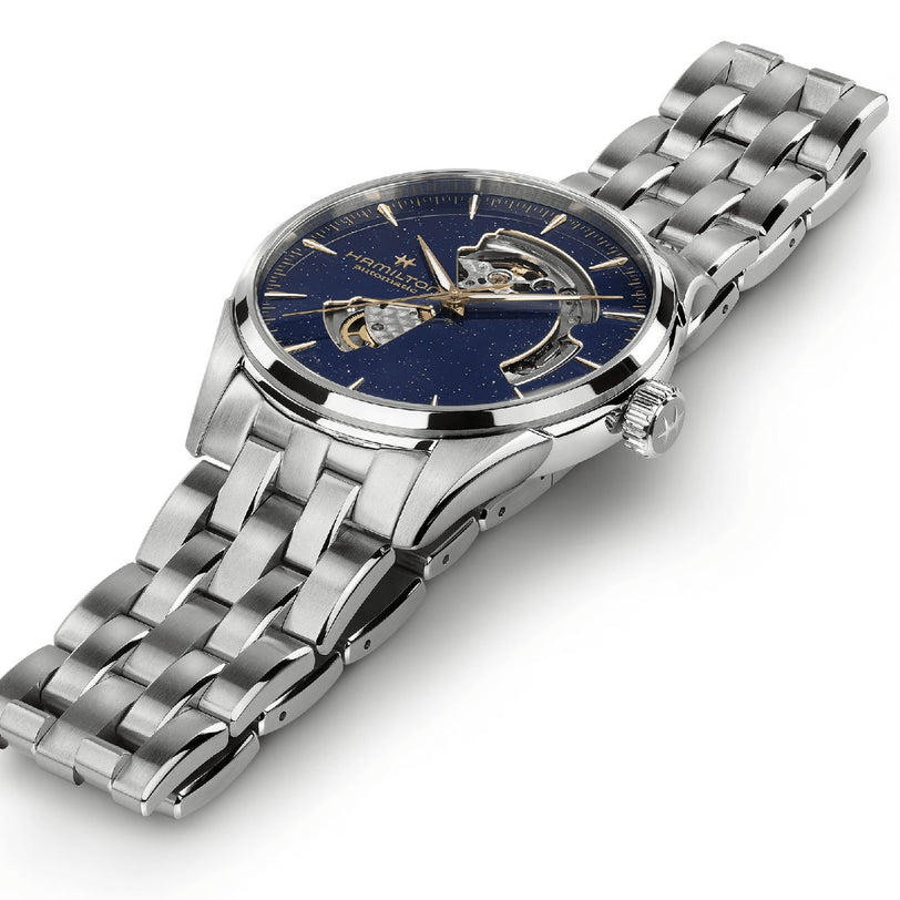 The Hamilton Jazzmaster Open Heart Auto 42mm features a stainless steel case, blue skeleton dial with silver hour markers, linked metal bracelet, and reliable automatic movement for a refined dress watch style.