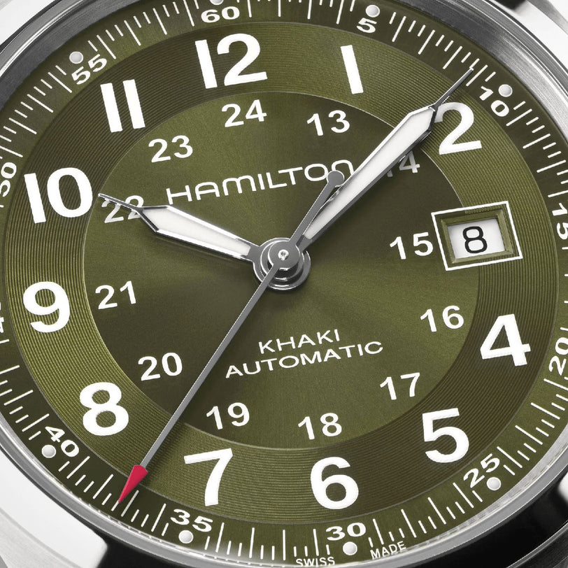 Close-up of the Hamilton Khaki Field Auto 42mm, showcasing an olive green dial with white numerals, date at 3 o’clock, luminous hands, and powered by the H-10 automatic movement—a nod to its military heritage.