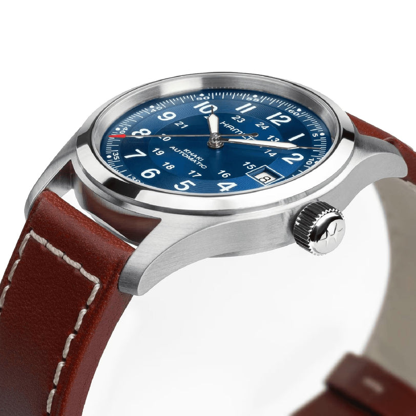 The Hamilton Khaki Field Auto 38mm features a silver case, navy sunray dial with white numerals and date, and a brown leather strap with white stitching, powered by the precise H-10 automatic movement.