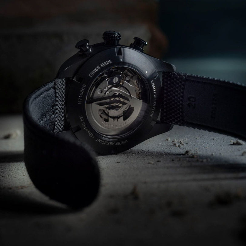Close-up of a black wristwatch with visible brand name on a dark background