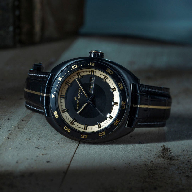 Hamilton watch with black leather strap on a textured surface