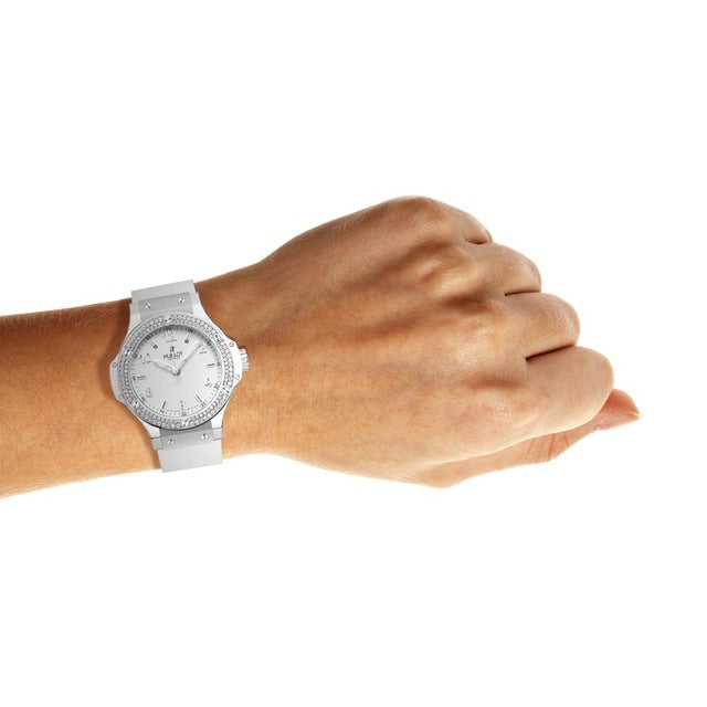 A left hand with a light skin tone wears the Hublot Big Bang Steel White Diamonds wristwatch, featuring a stainless steel bezel, shown against a plain white background.