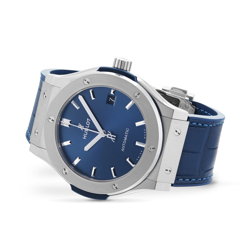 The Hublot Classic Fusion Titanium Blue features a titanium case, blue sunray dial, silver hour markers and hands, and a blue textured strap, shown against a white background.