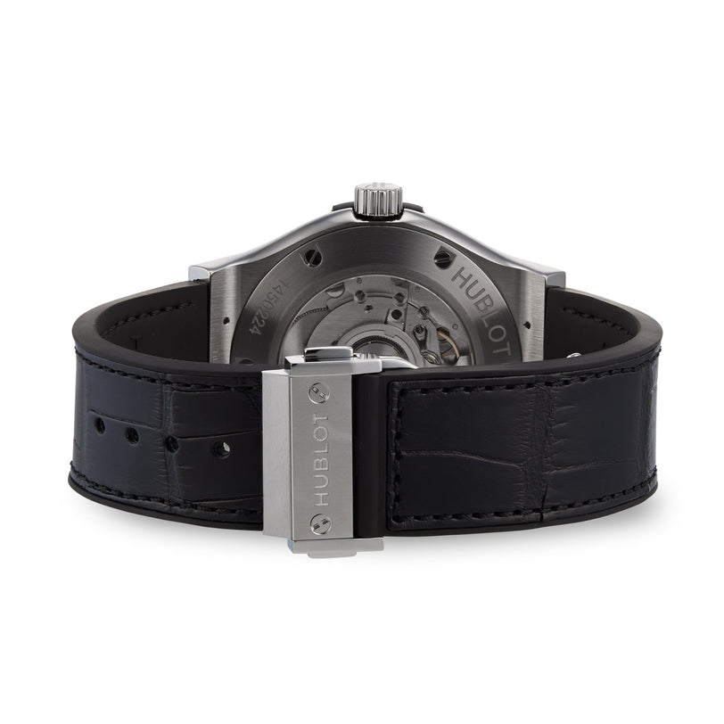 The image shows the back of a Hublot Classic Fusion Titanium watch, featuring a black leather strap, titanium case, stainless steel clasp, and an exhibition case back displaying the automatic movement.