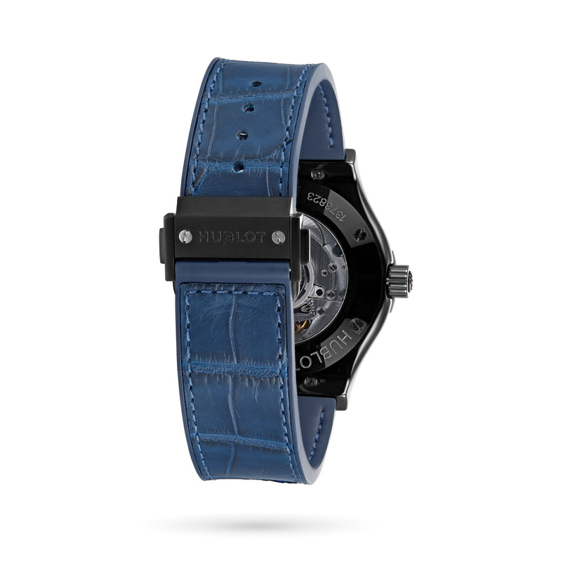 A close-up of the back of a Hublot Classic Fusion Ceramic Blue wristwatch with a blue alligator leather strap, black clasp, and partially visible transparent case back revealing the automatic movement.