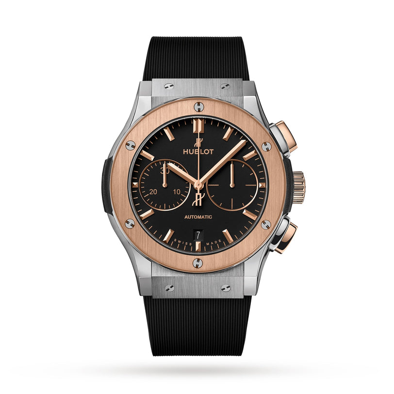 The Hublot Classic Fusion Chronograph Titanium King Gold features a black dial, gold bezel with visible screws, three subdials, and a black rubber strap, showcased against a white background.
