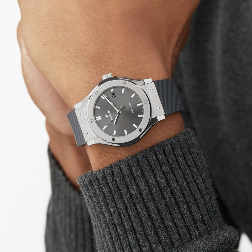 Someone wearing a Hublot Classic Fusion Racing Grey Titanium watch paired with a gray ribbed sweater.
