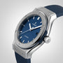 The Hublot Classic Fusion Titanium Blue features a titanium case, blue sunray dial, rubber strap, and automatic movement, displayed against a plain white background.
