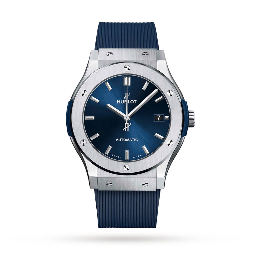 The Hublot Classic Fusion Titanium Blue watch features a blue dial, silver hour markers, date display, and a grade 5 titanium case with a blue rubber strap, displayed against a white background.