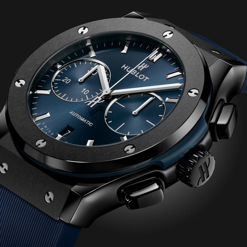 Close-up of a Hublot Classic Fusion Ceramic Blue Chronograph, featuring a blue sunray dial with three subdials, silver hour markers and hands, a black ceramic case, and a blue strap against a dark background.