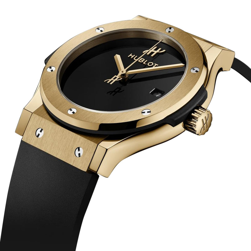 Hublot Classic Fusion Original Yellow Gold wristwatch featuring a black dial with minimal hour markers and a black rubber strap, displayed at an angle against a white background.