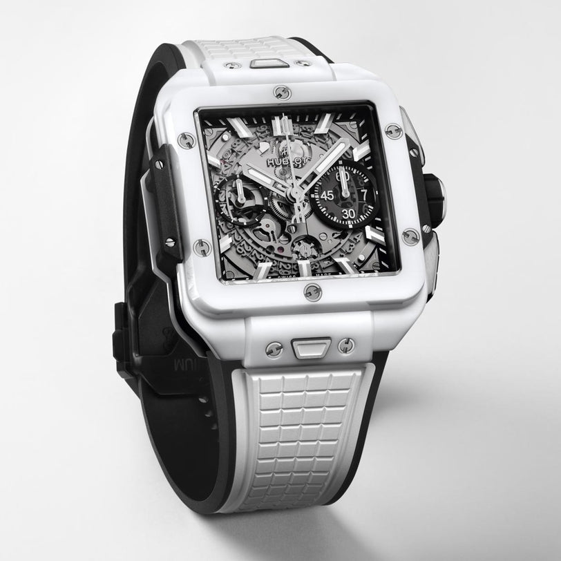 The Hublot Square Bang Unico White Ceramic wristwatch features a ceramic case, skeleton dial, and textured strap, showcased against a plain light background.