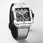 The Hublot Square Bang Unico White Ceramic wristwatch features a ceramic case, skeleton dial, and textured strap, showcased against a plain light background.