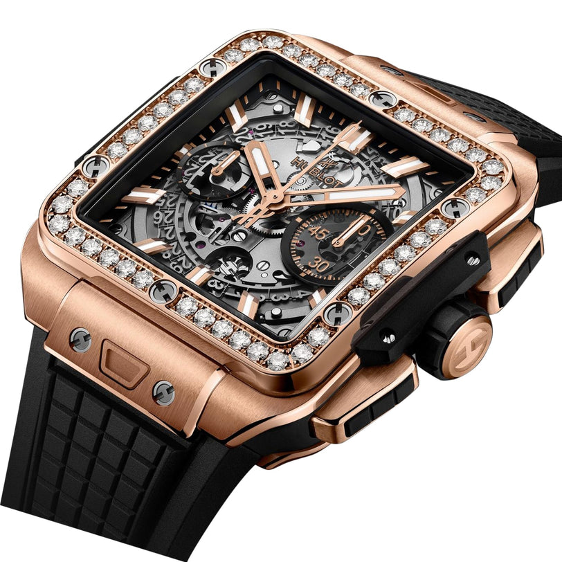 The Hublot Square Bang Unico King Gold Diamonds is a luxury wristwatch with a diamond-studded King Gold case, black rubber strap, and an exposed Unico movement visible on the dial.
