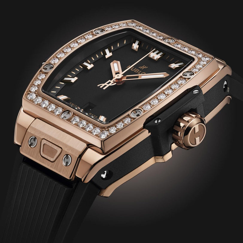 The Hublot Spirit Of Big Bang King Gold Diamonds wristwatch features a black face, 18K King gold case, diamond-set bezel, and black strap, displayed against a dark background.