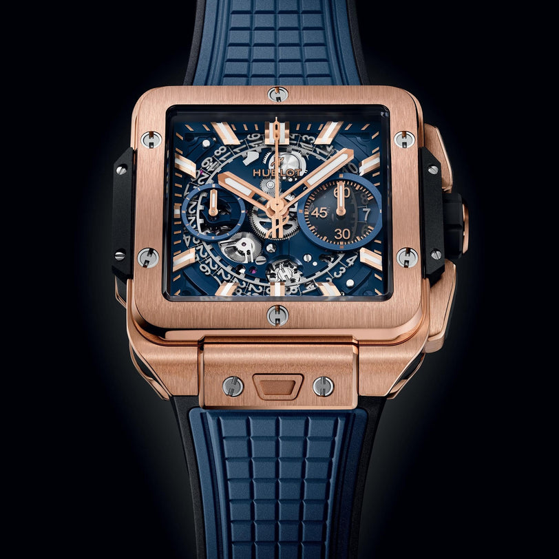 The Hublot Square Bang Unico King Gold Blue features a rose gold case, blue skeleton dial, blue rubber strap, exposed gears, and chronograph flyback subdials, set against a black background.