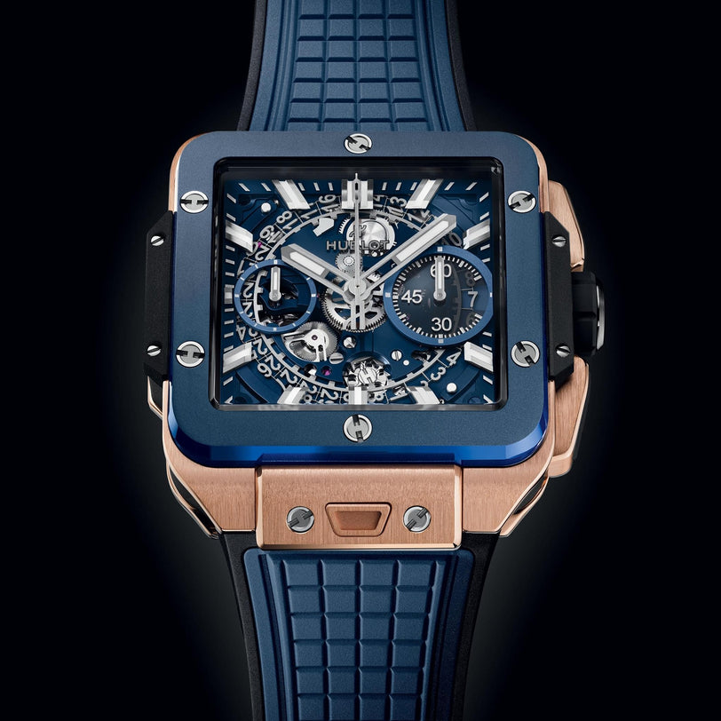 The Hublot Square Bang Unico King Gold Blue Ceramic watch showcases a blue dial, chronograph flyback, visible movement, and a textured blue rubber strap in a bold blue and King Gold case.