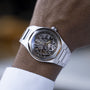 A close-up of a person wearing the Girard-Perregaux Laureato Skeleton wristwatch, featuring a silver skeleton dial with visible gears, an octagonal bezel, and a stainless steel band.