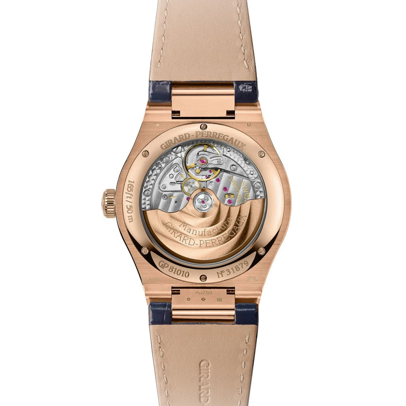 Back view of the Girard-Perregaux Laureato 42 reveals its exposed automatic movement and intricate mechanisms, paired with a tan leather strap, Pink Gold case, and striking Sage Green or Ultramarine Blue dials.