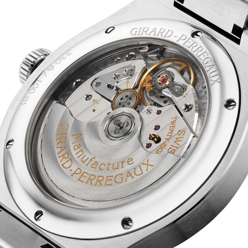 Close-up of the transparent case back of the Girard-Perregaux Laureato Fifty 42 Watches of Switzerland Exclusive, showcasing its intricate mechanical movement with engraved gold text and exposed gears inside a polished stainless steel casing.