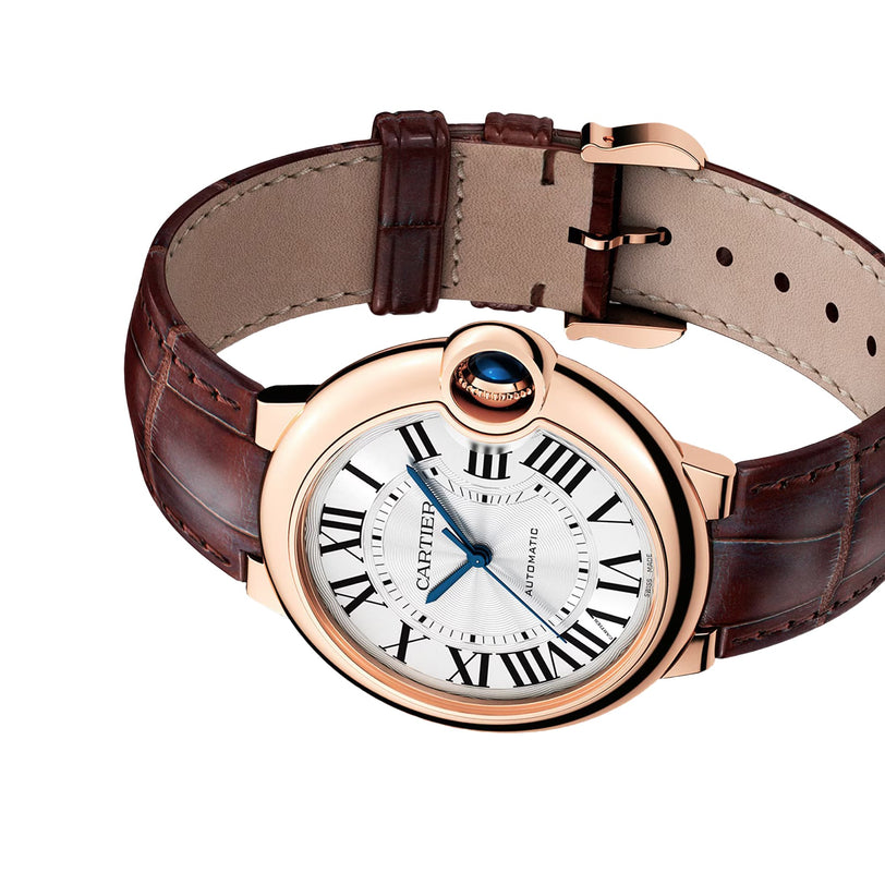 A Cartier Ballon Bleu de Cartier watch with a pink gold case, white guilloché dial, black Roman numerals, blue hands, and a brown leather strap is shown against a white background.