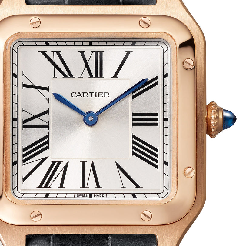 Close-up of the Cartier Santos-Dumont watch featuring a square 18K rose gold case, blue hands, Roman numeral hour markers, and a crown adorned with a blue gemstone.