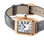 The Cartier Santos-Dumont is a luxury watch with an 18K rose gold square case, white dial with black Roman numerals, blue hands, and a grey leather strap.